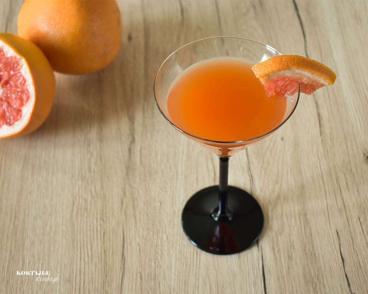 Ujęcie z góry na drink 212 Cocktail o pomarańczowej barwie, zbliżenie na kawałem grejpfruta.