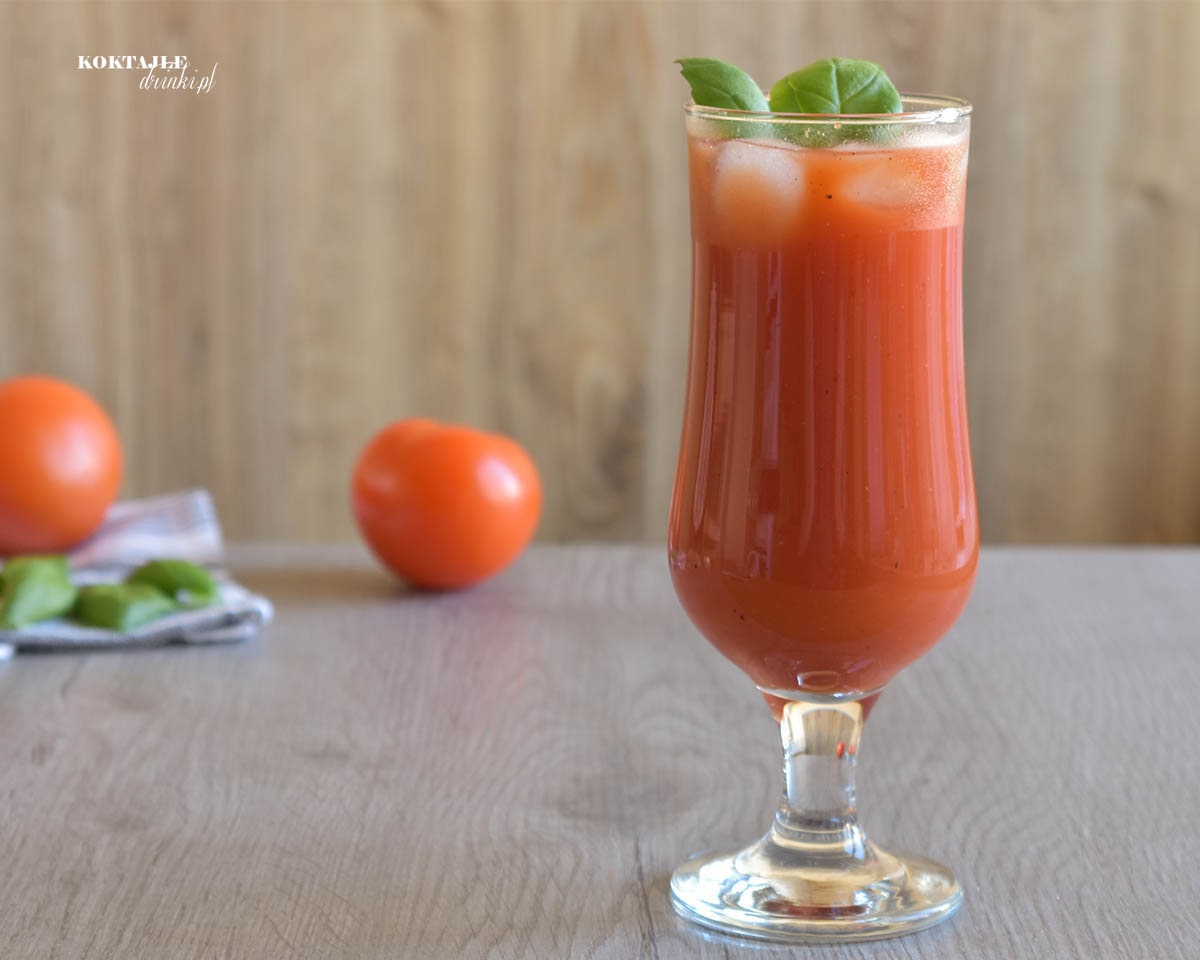 Drink z wódką Bloody Mary (Krwawa Mary) o barwie czerwonej w szklance ozdobionej listkami bazylii.