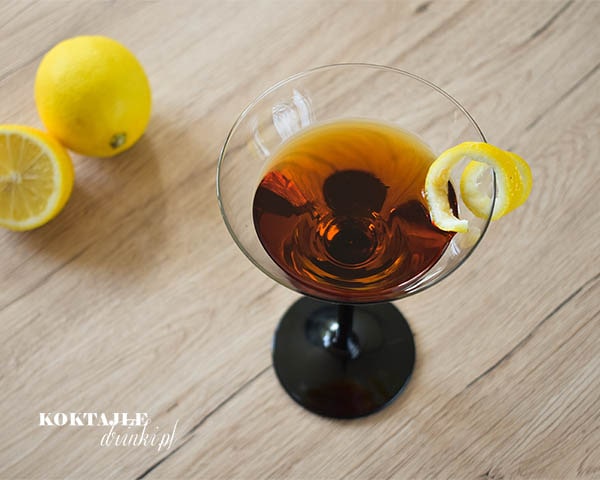 Ujęcie z góry na drink Count Mast Negroni o brązowej barwie, w kieliszku ozdobionym twistem ze skórki cytryny.