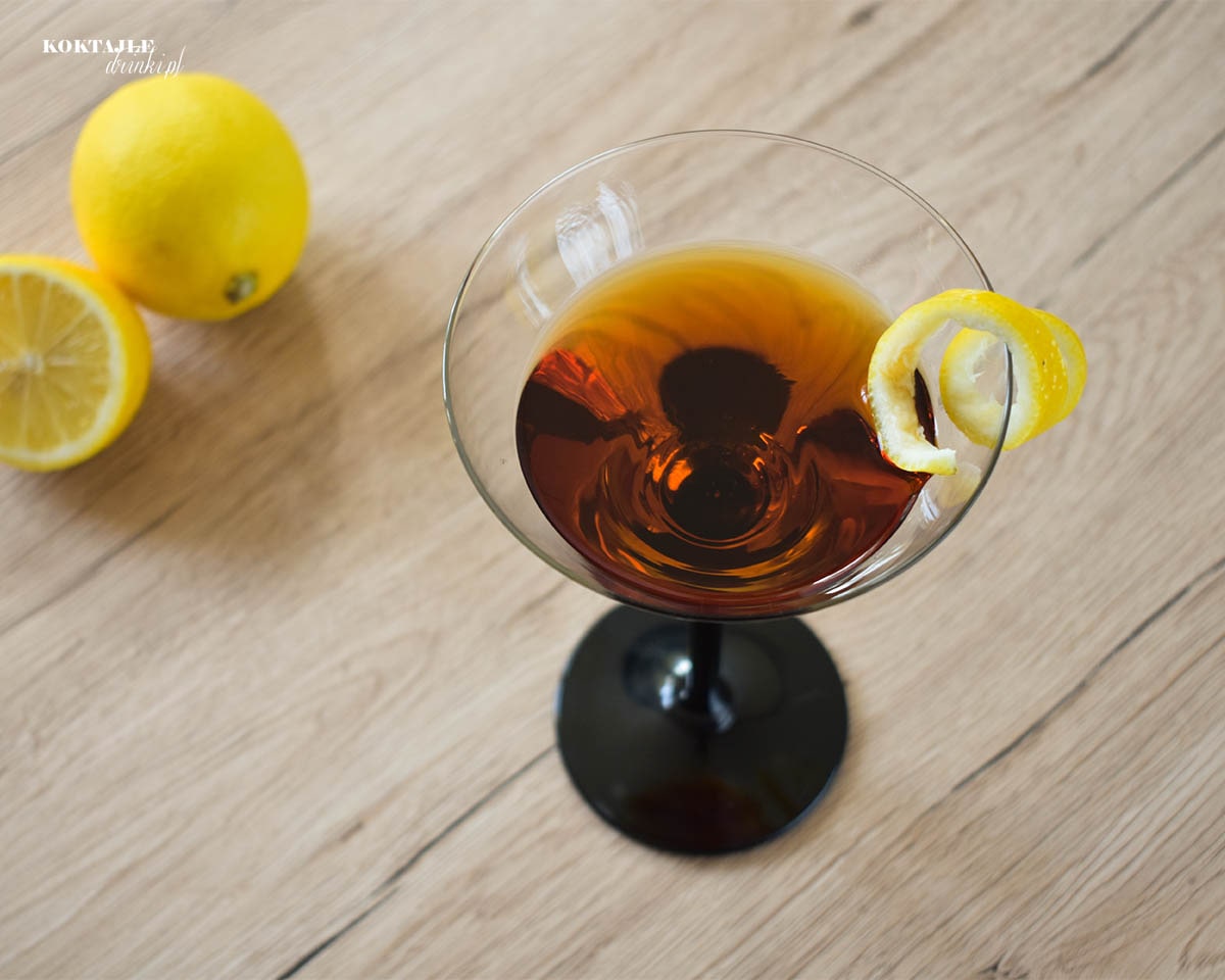 Ujęcie z góry na drink Count Mast Negroni o brązowej barwie, w kieliszku ozdobionym twistem ze skórki cytryny.
