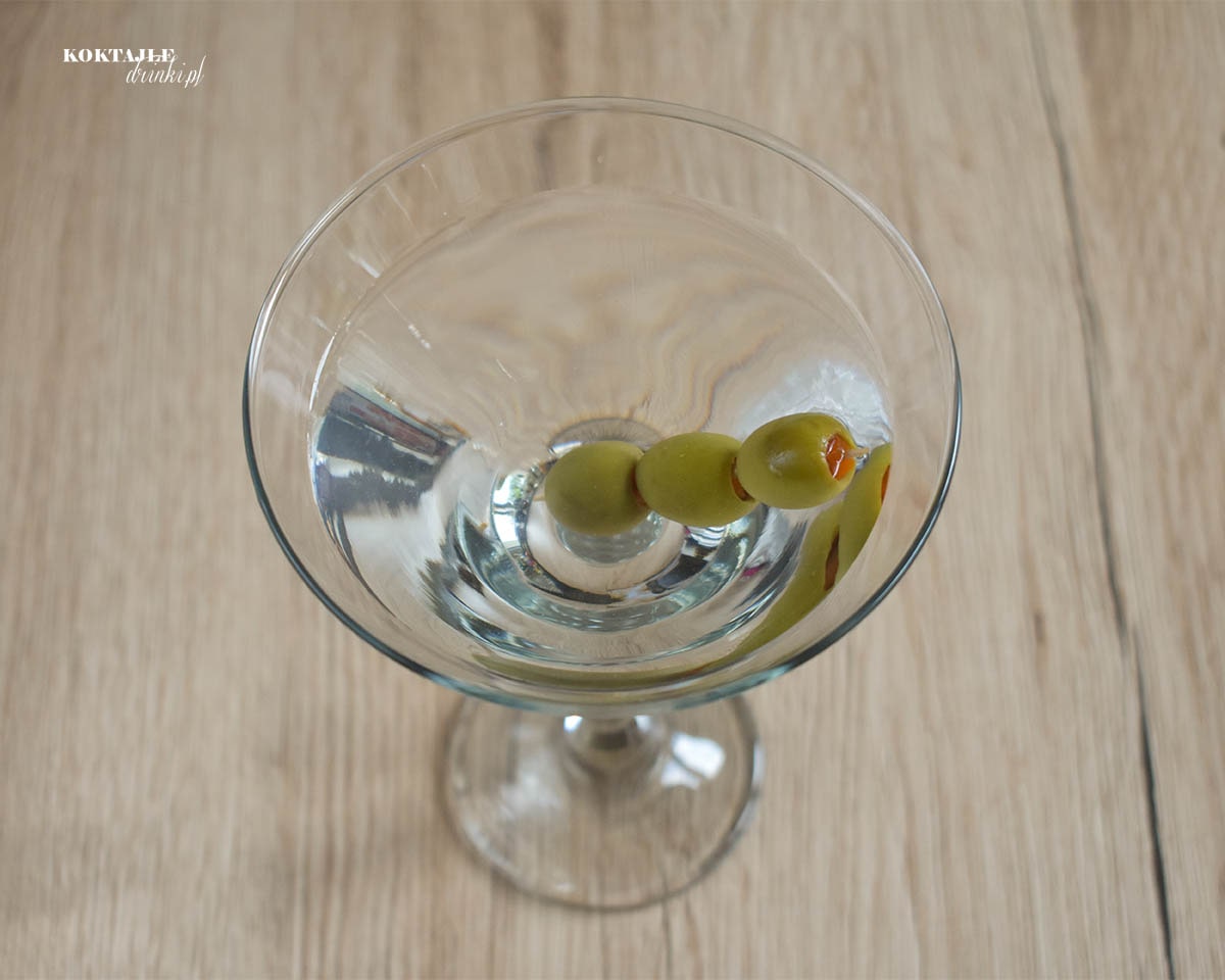 Drink z wermutem, Dry Martini w kieliszku o przezroczystej barwie z ozdobą 3 oliwek na wykałaczce.