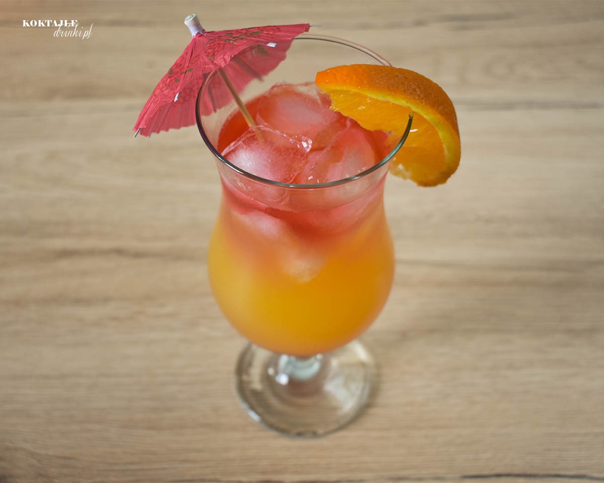 Ujęcie z góry na drink Hot Blooded, zbliżenie na ozdobę w postaci parasolki i kawałka pomarańczy.