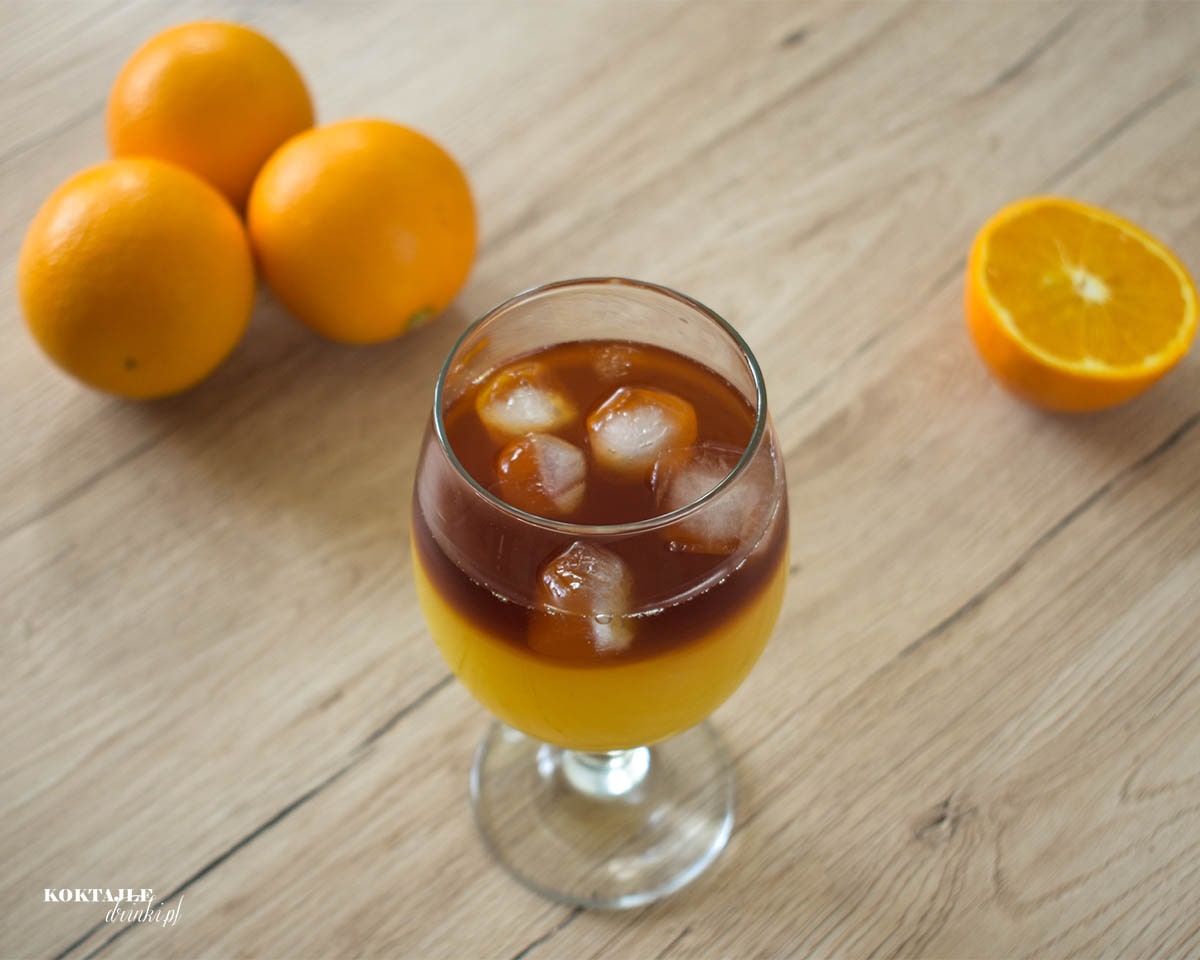 Drugie ujęcie na drink Jager Bullet o dwóch warstwach w otoczeniu pomarańczy.