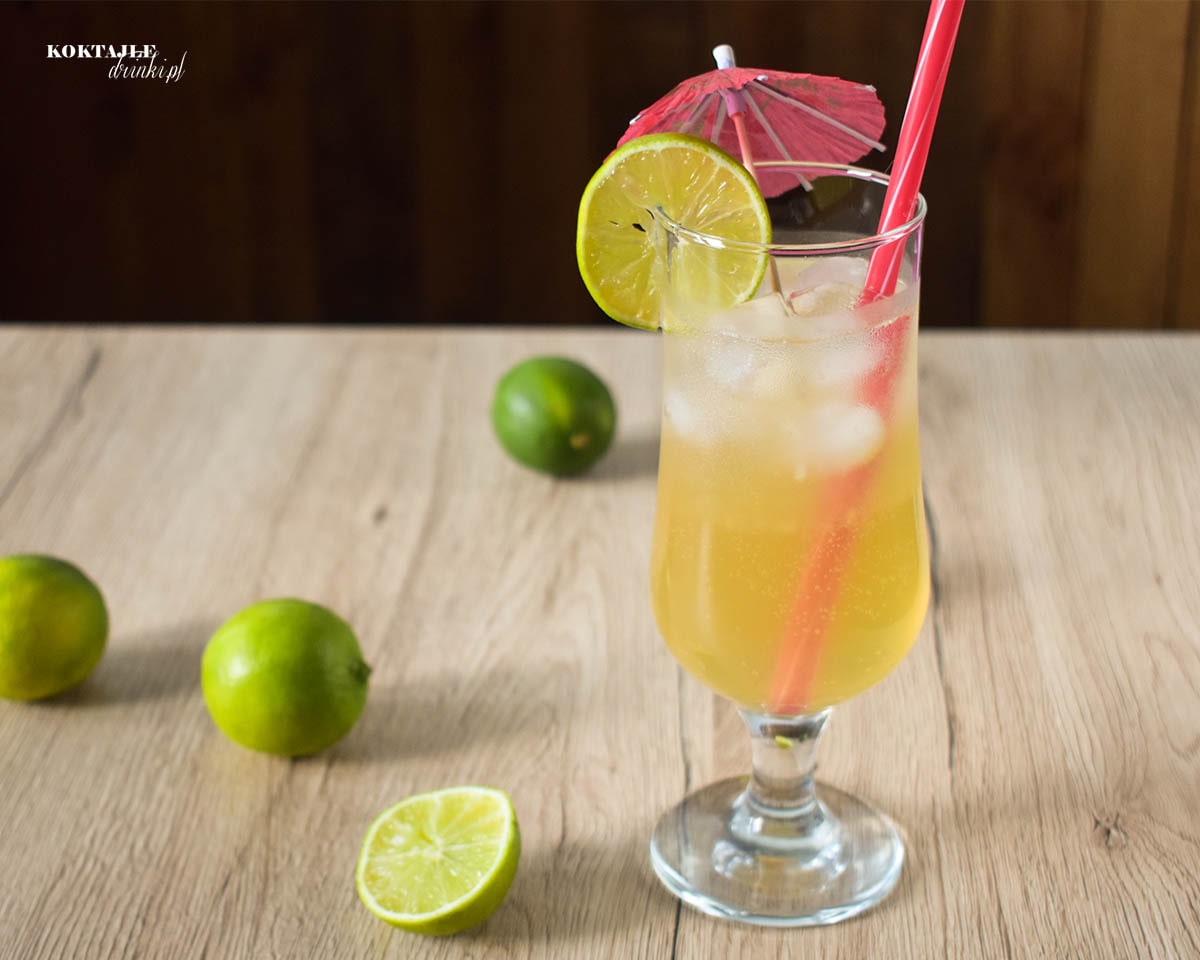 Drink Malibu Paloma w ujęciu drugim od frontu w szklance przyozdobionej parasolką i plastrem limonki.