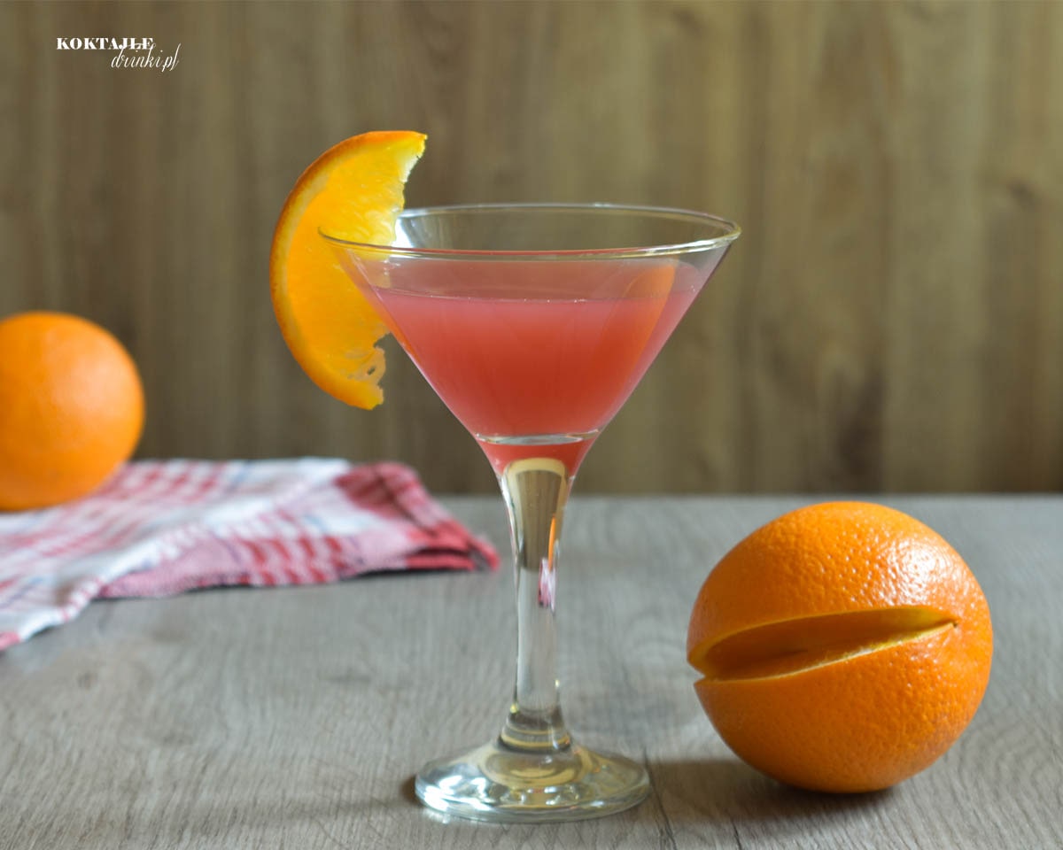 Drink Rum Cranberry o barwie czerwonej w szklance ozdobionej plastrem pomarańczy
