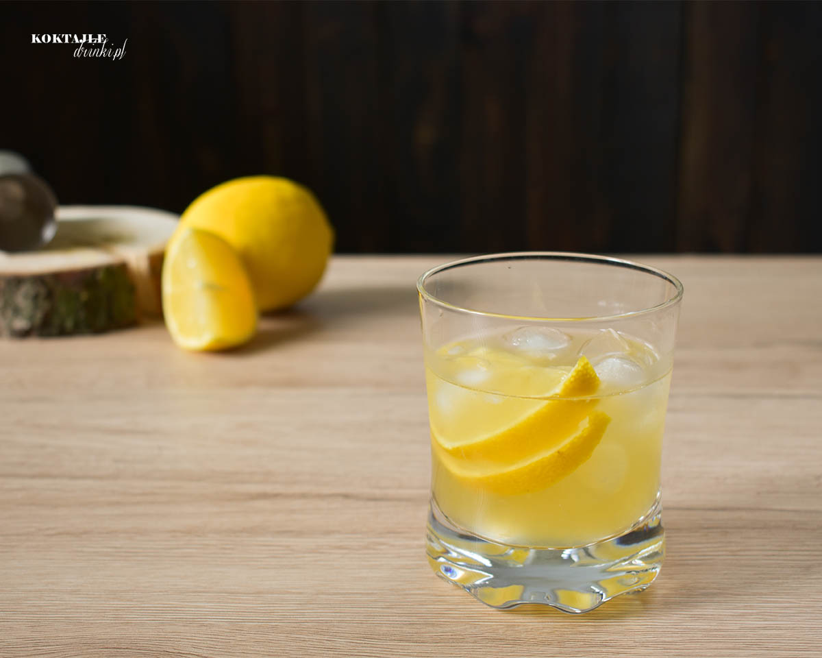 Drink whisky sour w ujęciu od frontu z dwoma plastrami cytryny w szklance.