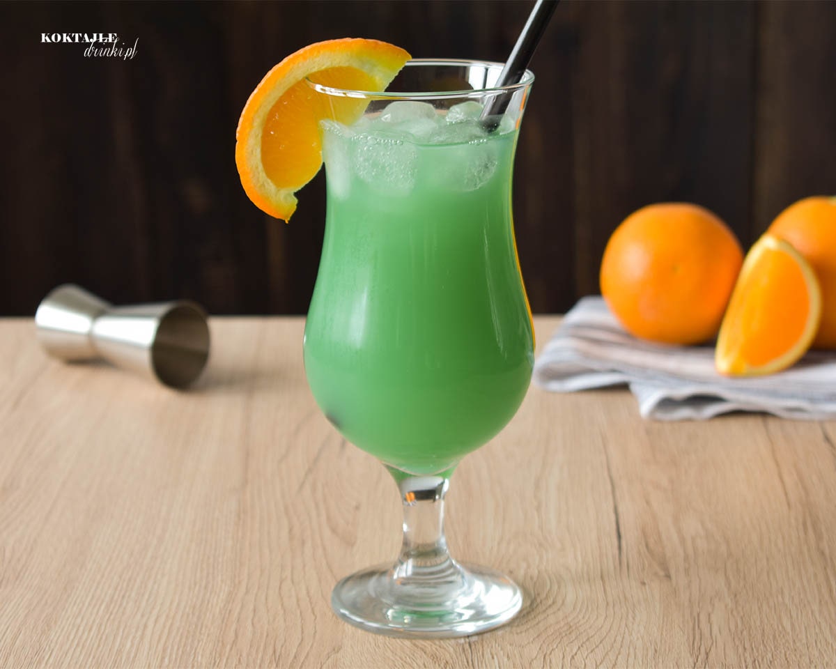 Drink z wódką, Zielona Ropucha widziany od frontu w kieliszku ozdobionym kawałkiem pomarańczy.