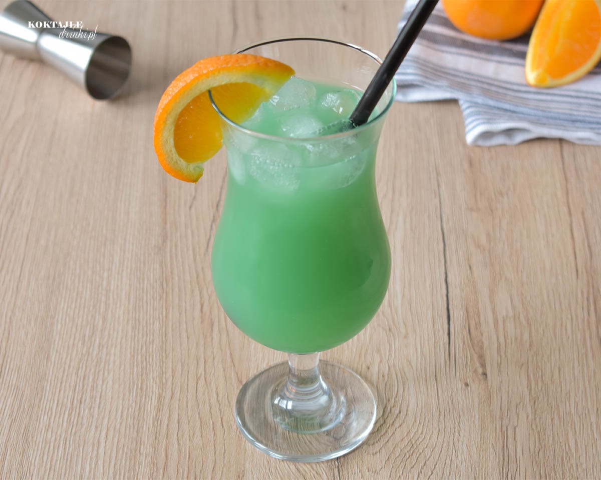 Ujęcie drugie na drink Zielona Ropucha tym razem z góry, zbliżenie na kawałek pomarańczy zawieszony na szklance.
