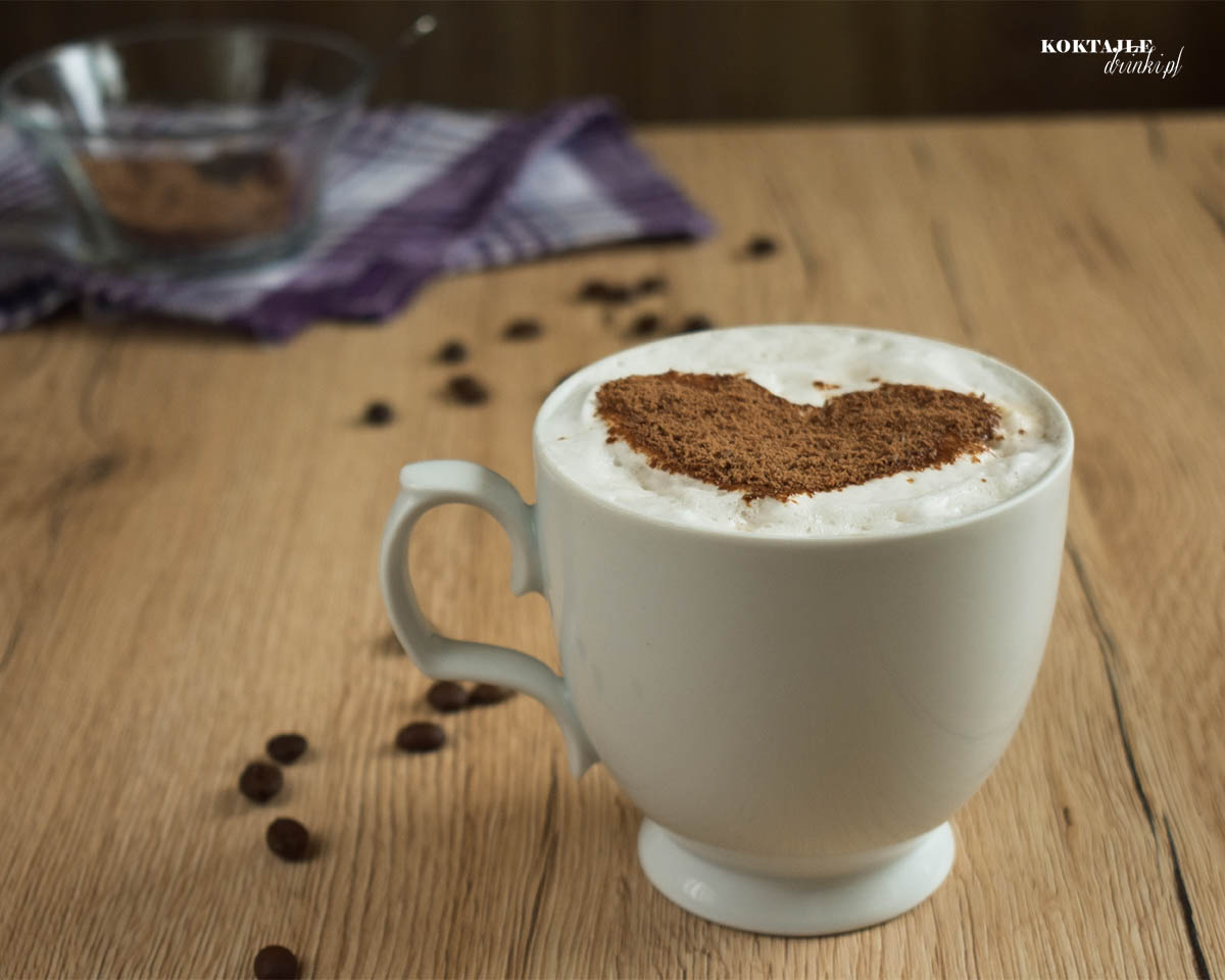 Kawa Caffe Latte z posypką czekolady na piance, na drugim planie widoczne naczynie z wiórkami czekolady.