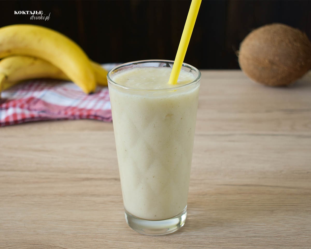 Koktajl owocowy smoothie o barwie białej, w tle kokos i banany.