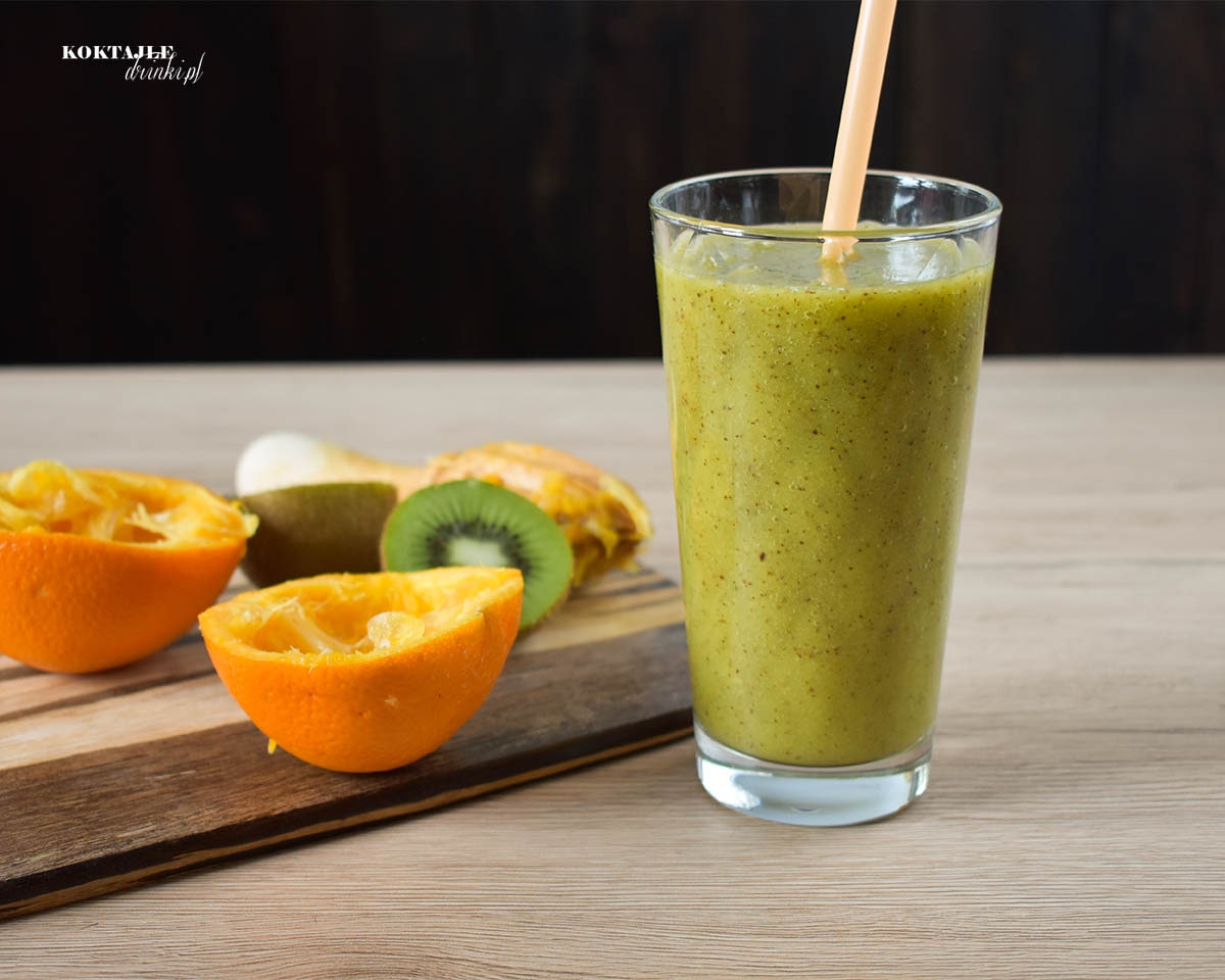 Koktajl owocowy smoothie o zielonej barwie, w otoczeniu wyciśniętej pomarańczy i kiwi.