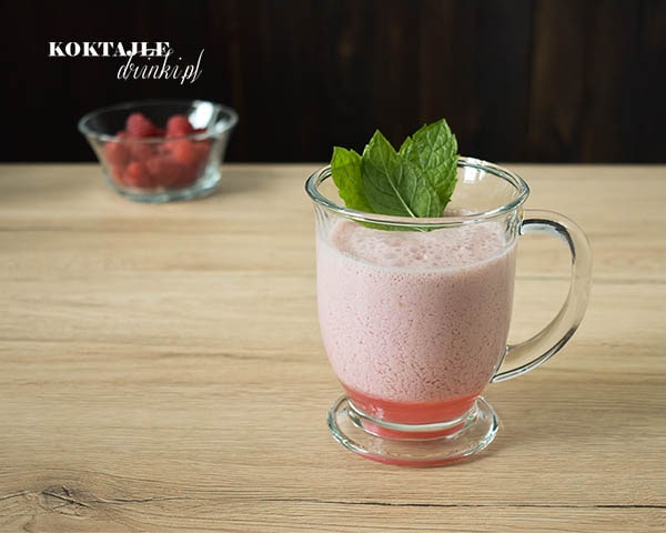 Koktajl smoothie owocowy o barwie jasno fioletowej w szklance ozdobionej liśćmi mięty.