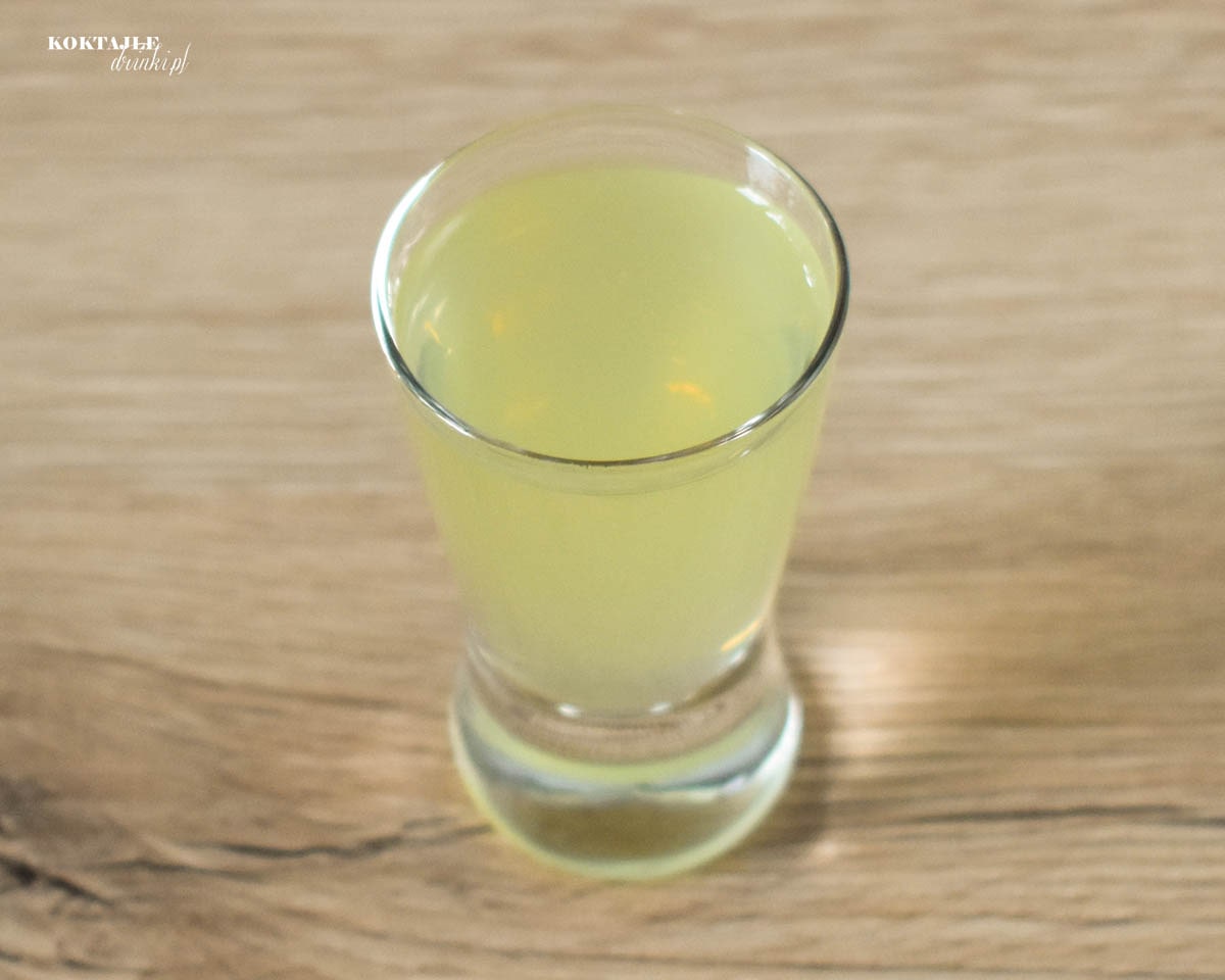 Widok z góry na shot cytryna i wódka o jasno żółtej barwie.